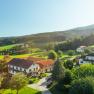 Pohled na dům, © Wiener Alpen / Martin Fülöp Venkovská krajina s domy, loukami a lesem v pozadí.