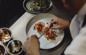 Kuchyně: odvážná, divoká, zakořeněná v regionu, © Niederösterreich Werbung/Sophie Menegaldo Kuchař připravuje pokrm na talíři.