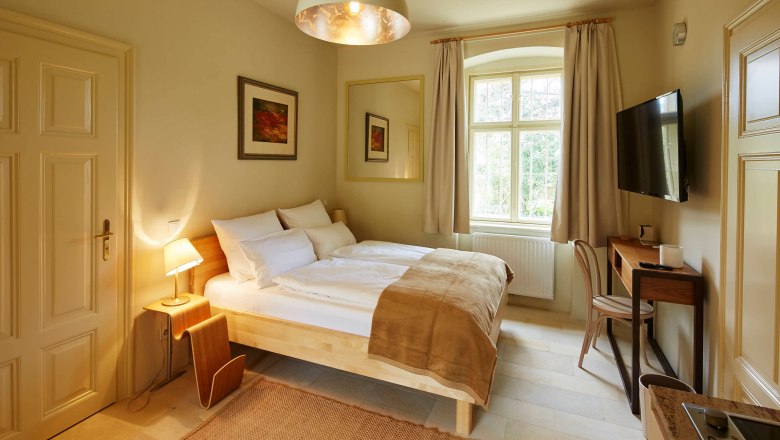 Byt Steinfeld ve vile Tranquillini, © Herbert Lehmann Útulná ložnice s manželskou postelí, psacím stolem a velkým oknem.