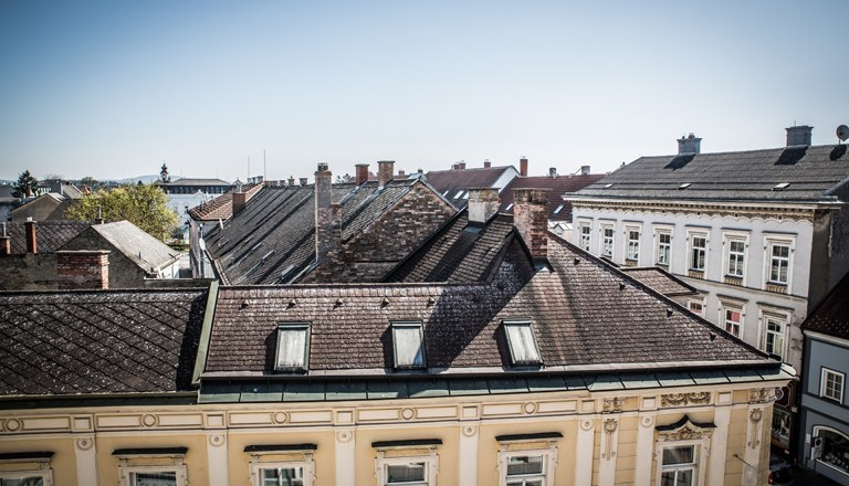 Room view, © flotographix Ausblick auf Dächer der Nachbargebäude und blauem Himmel.