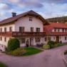 Farma Dissauer Family Rosinger, © Niederösterreich Werbung / Maximilian Pawlikowsky Tradiční statek s červenou střechou a balkonem, obklopený zelení a stromy.