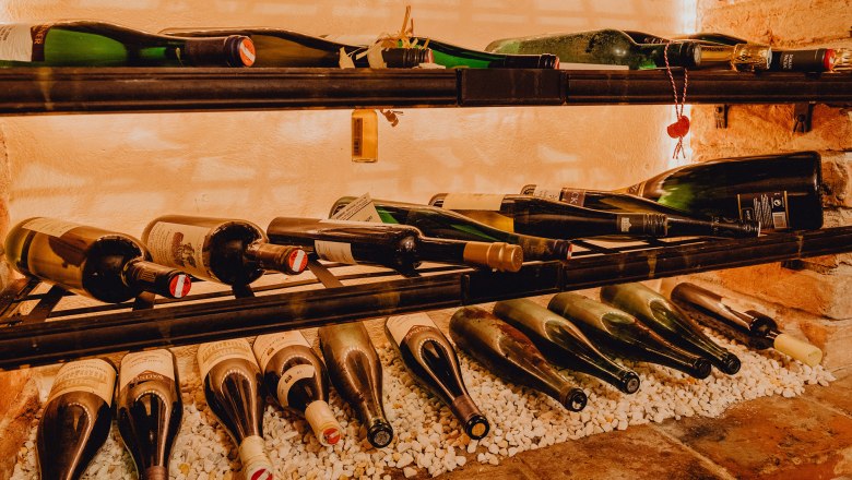 Široká nabídka vín, © Niederösterreich Werbung/Klaus Engelmayer Láhve vína na polici na bílých kamenech.