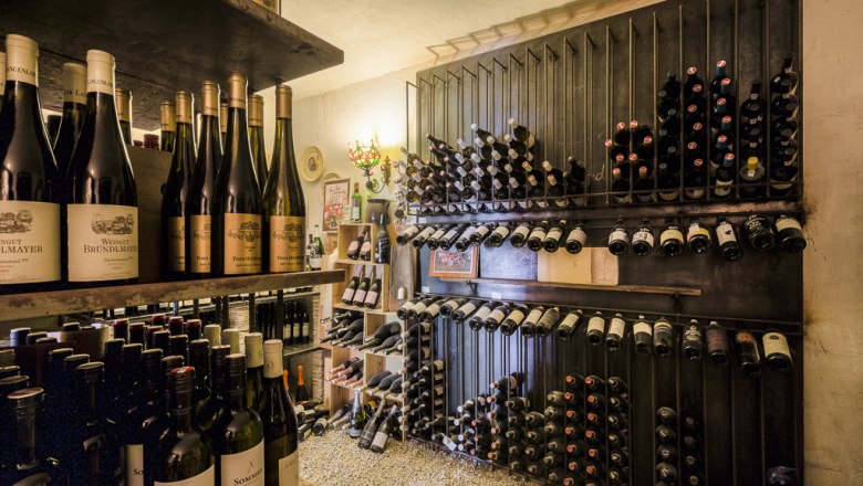 Vinný sklep, © Lukas Kirchgasser Vinný sklípek s policemi plnými úhledně naskládaných lahví vína.