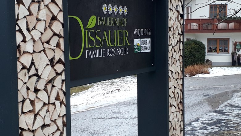 Soudní rada, © rosinger Znak farmy s hromadami dřeva a domem v pozadí.