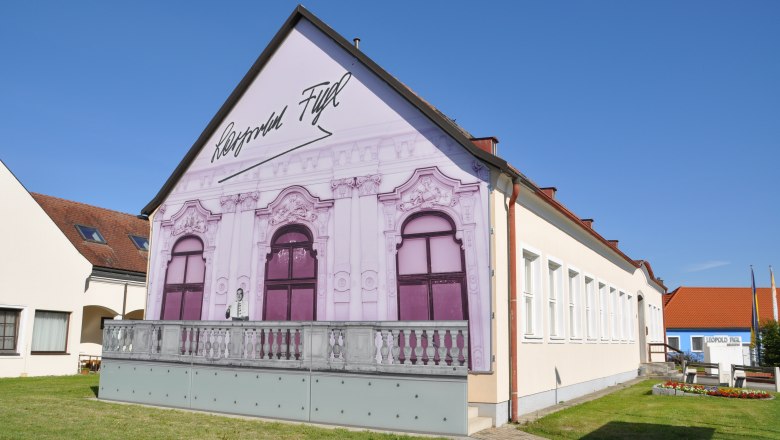 Leopold Figl Museum, © Stadtgemeinde Michelhausen Leopold Figl Museum mit bemalter Fassade und blauen Himmel.