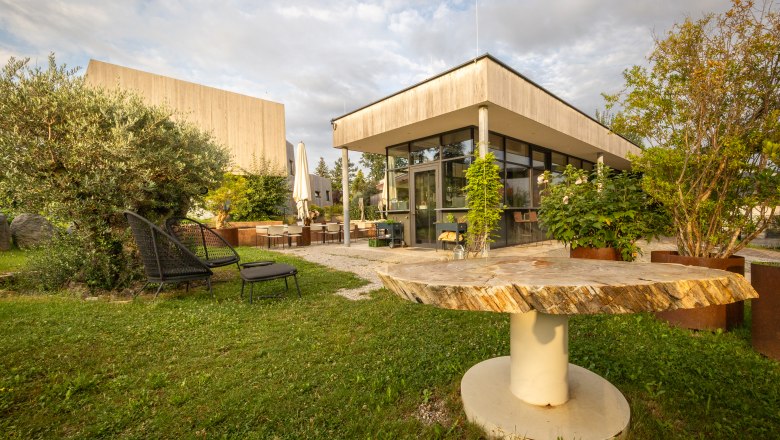 Naturhotel Gut Guntrams Gartenlofts, © Niederösterreich Werbung / Maximilian Pawlikowsky Zahrada moderního hotelu s posezením a rostlinami.