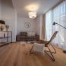 Apartmány Hausgnost, © Niederösterreich Werbung / Maximilian Pawlikowsky Moderně zařízený obývací pokoj s pohovkou, křeslem, stojací lampou a velkým oknem se závěsy.