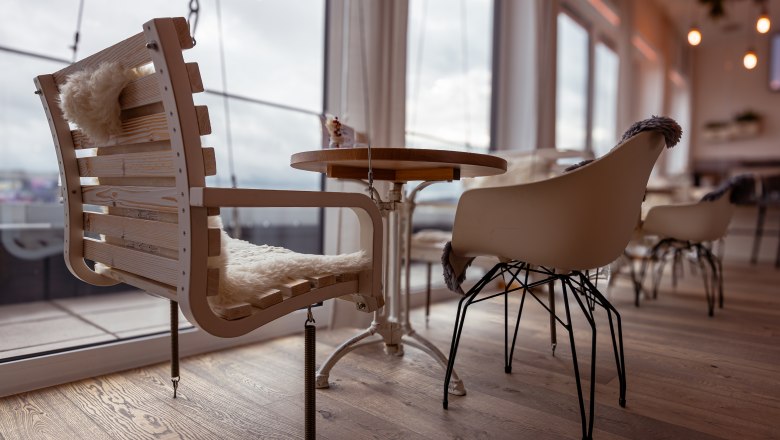 Alfred, © Niederösterreich Werbung / Maximilian Pawlikowsky Pohled do interiéru kavárny s moderními židlemi a dřevěným stolem, v pozadí velká okna.