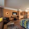 Boutique hotel WeinSpitz, © Niederösterreich Werbung / Maximilian Pawlikowsky Moderní hotelový pokoj s dřevěným obložením, pohovkou, postelí a TV s plochou obrazovkou.