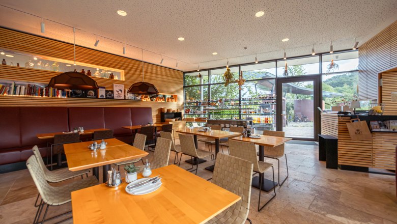 Naturhotel Gut Guntrams Gartenlofts, © Niederösterreich Werbung / Maximilian Pawlikowsky Pohled do interiéru moderní restaurace s dřevěnými stoly a velkými okny.