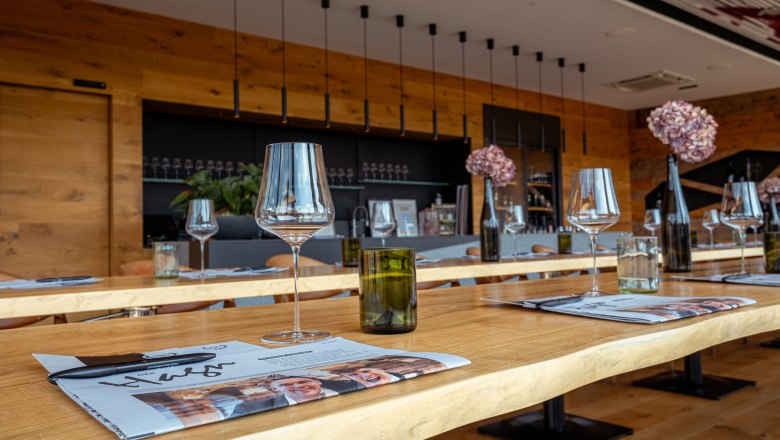 Vinařský dům Hagn, © Niederösterreich Werbung / Maximilian Pawlikowsky Pohled do interiéru moderního vinařského domu s položenými stoly, sklenicemi na víno a dekoracemi.