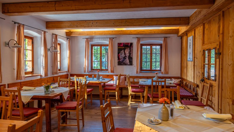 Postel ve Wies'n, © Niederösterreich Werbung / Maximilian Pawlikowsky Útulná jídelna s dřevěným nábytkem a prostřenými stoly.