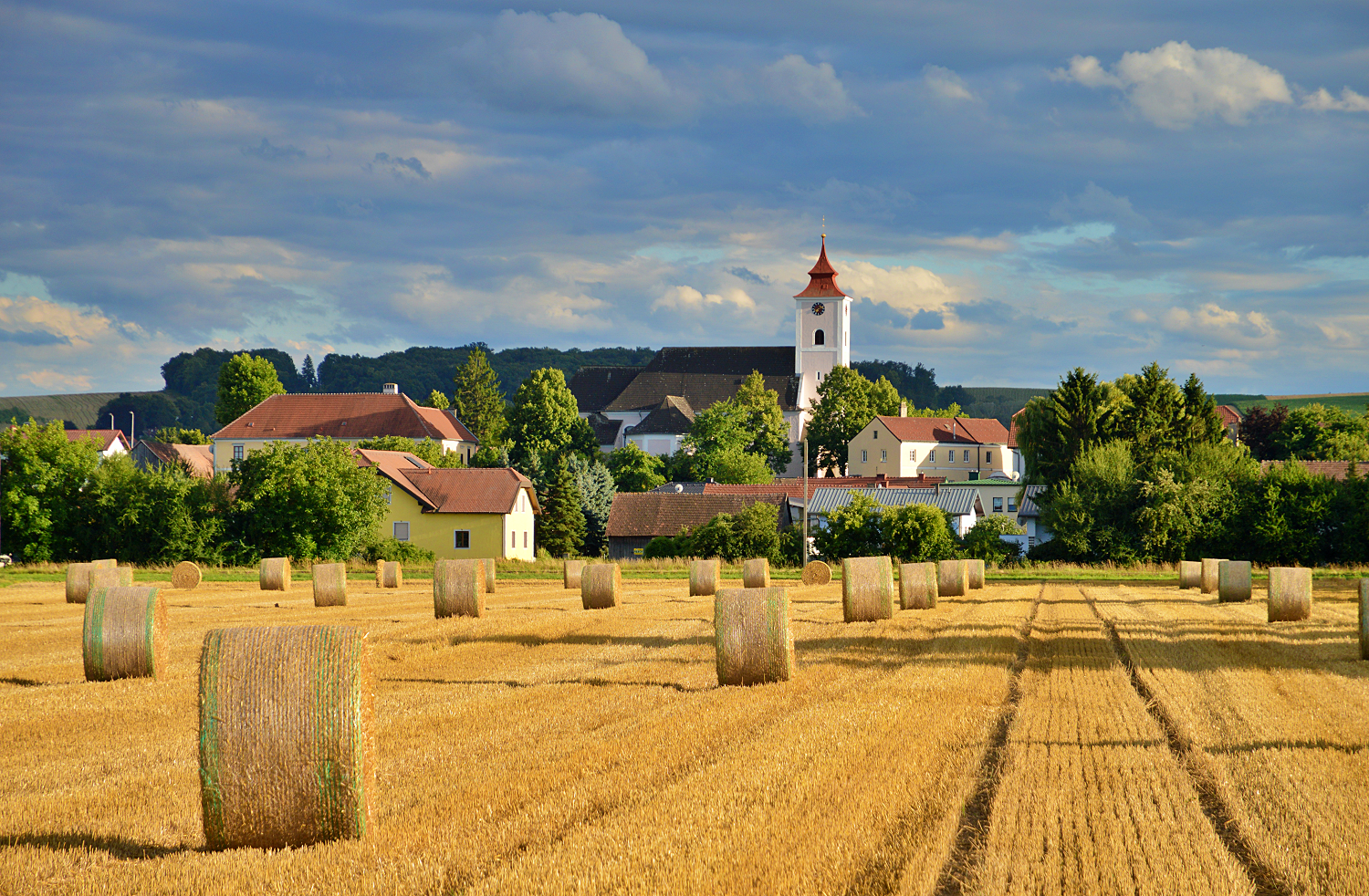 Krajina s balíky slámy a kostelem v Michelhausenu.