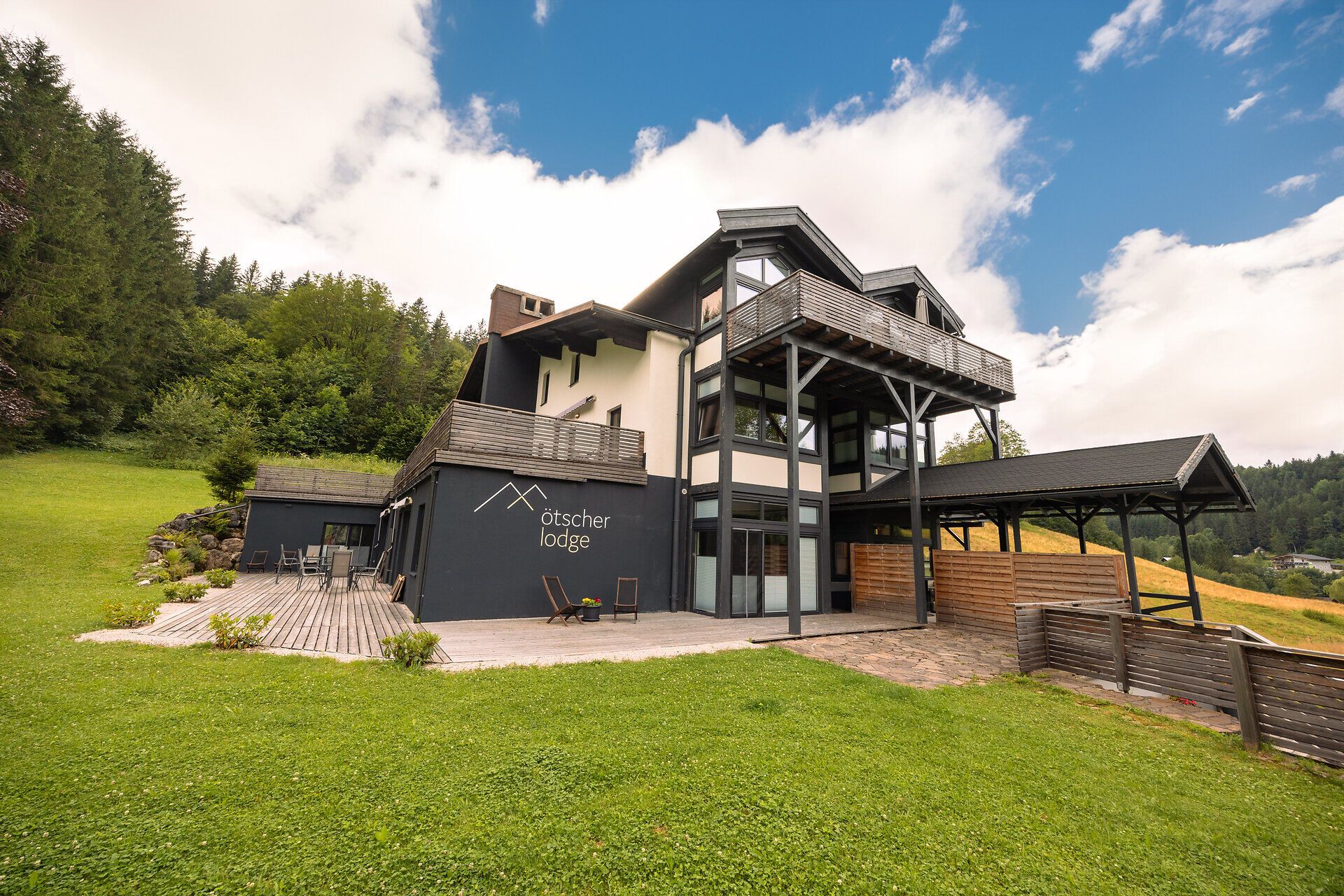 Ötscher Lodge v zeleném, zalesněném prostředí s modrou oblohou.