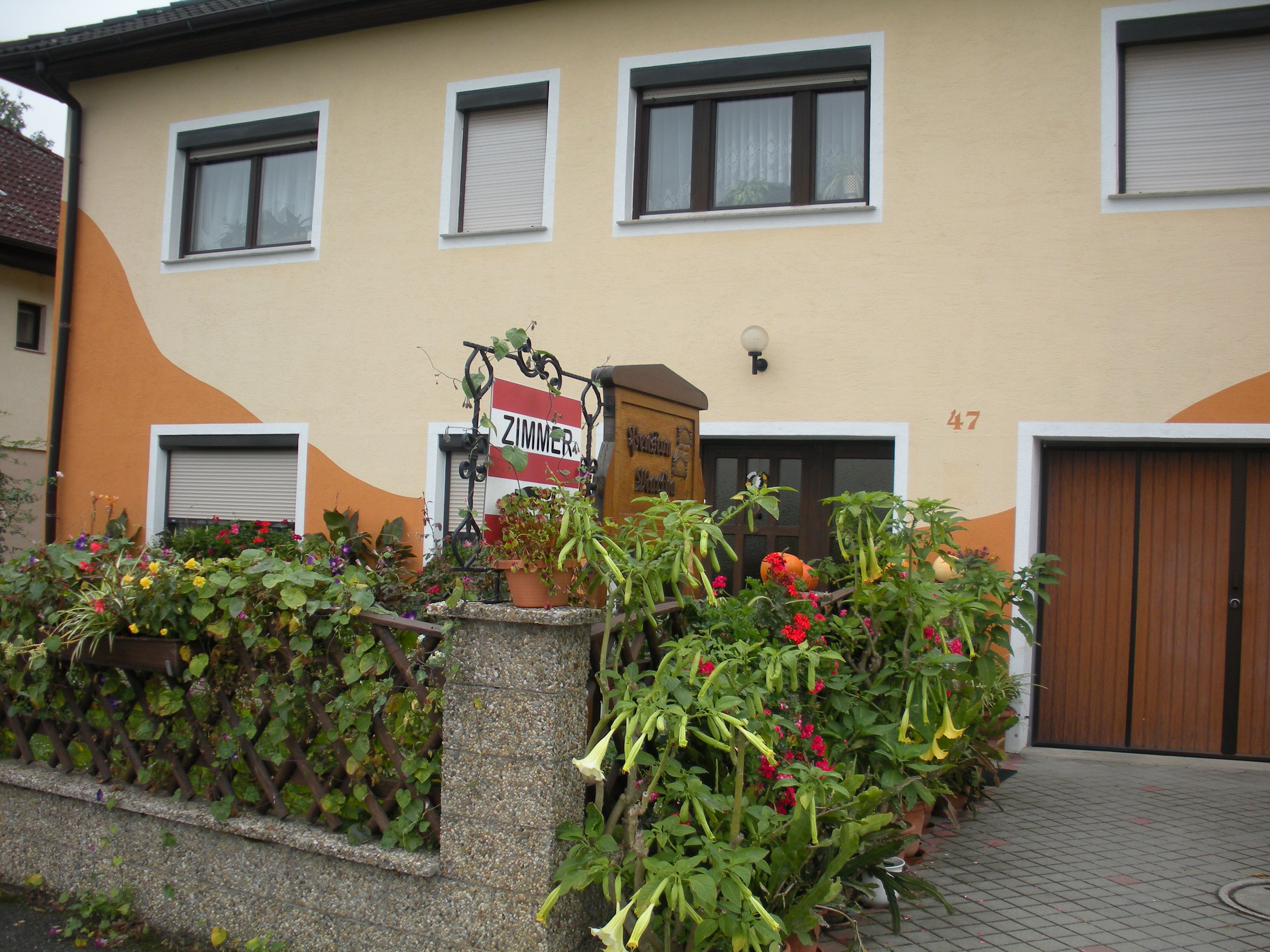 Dům se žlutou fasádou, květinovým dekorem a nápisem "Room".