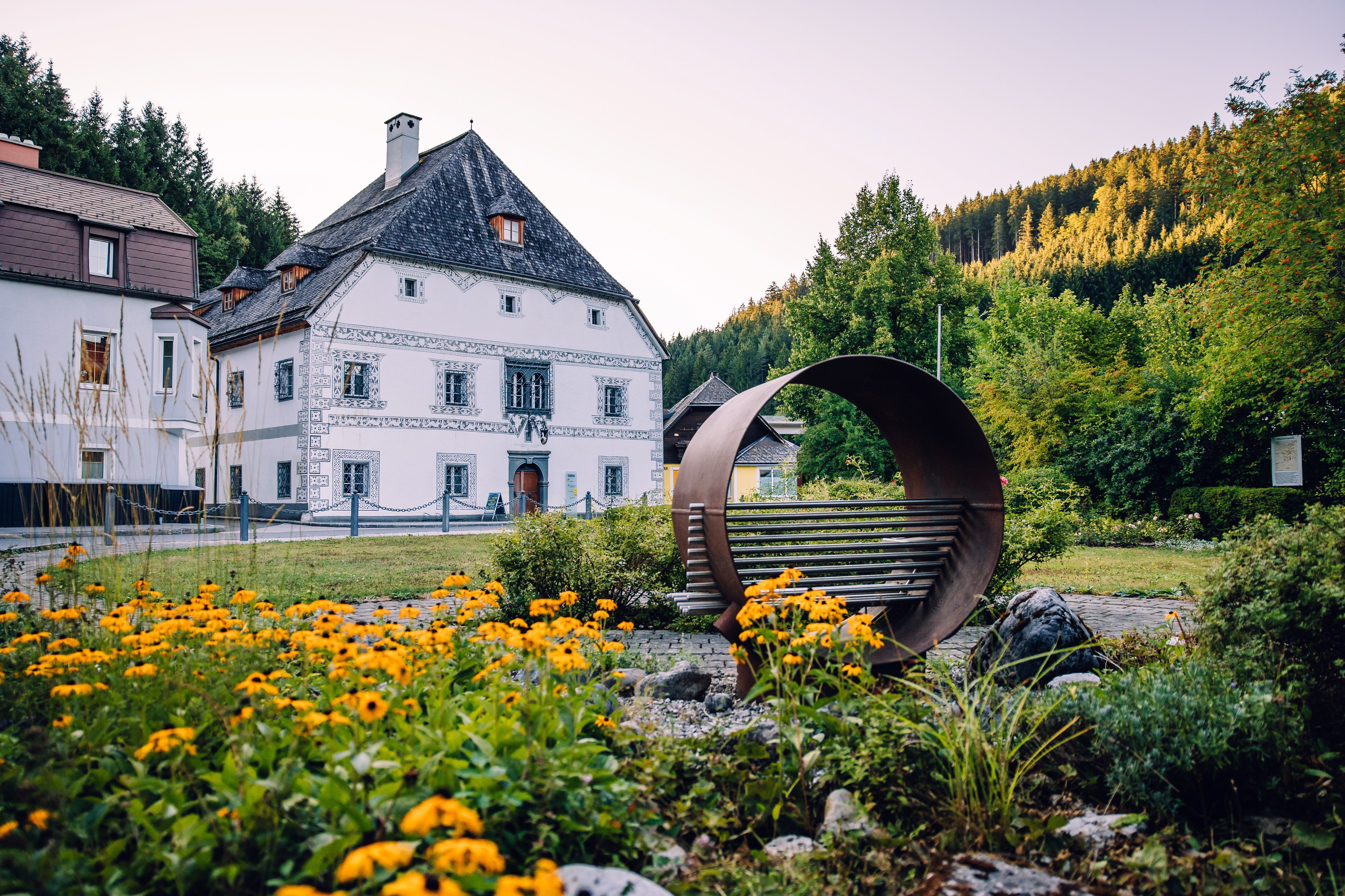 Dům Amonhaus v Lunz am See, v popředí je křeslo pro poslech a před historickou budovou je květinový záhon.