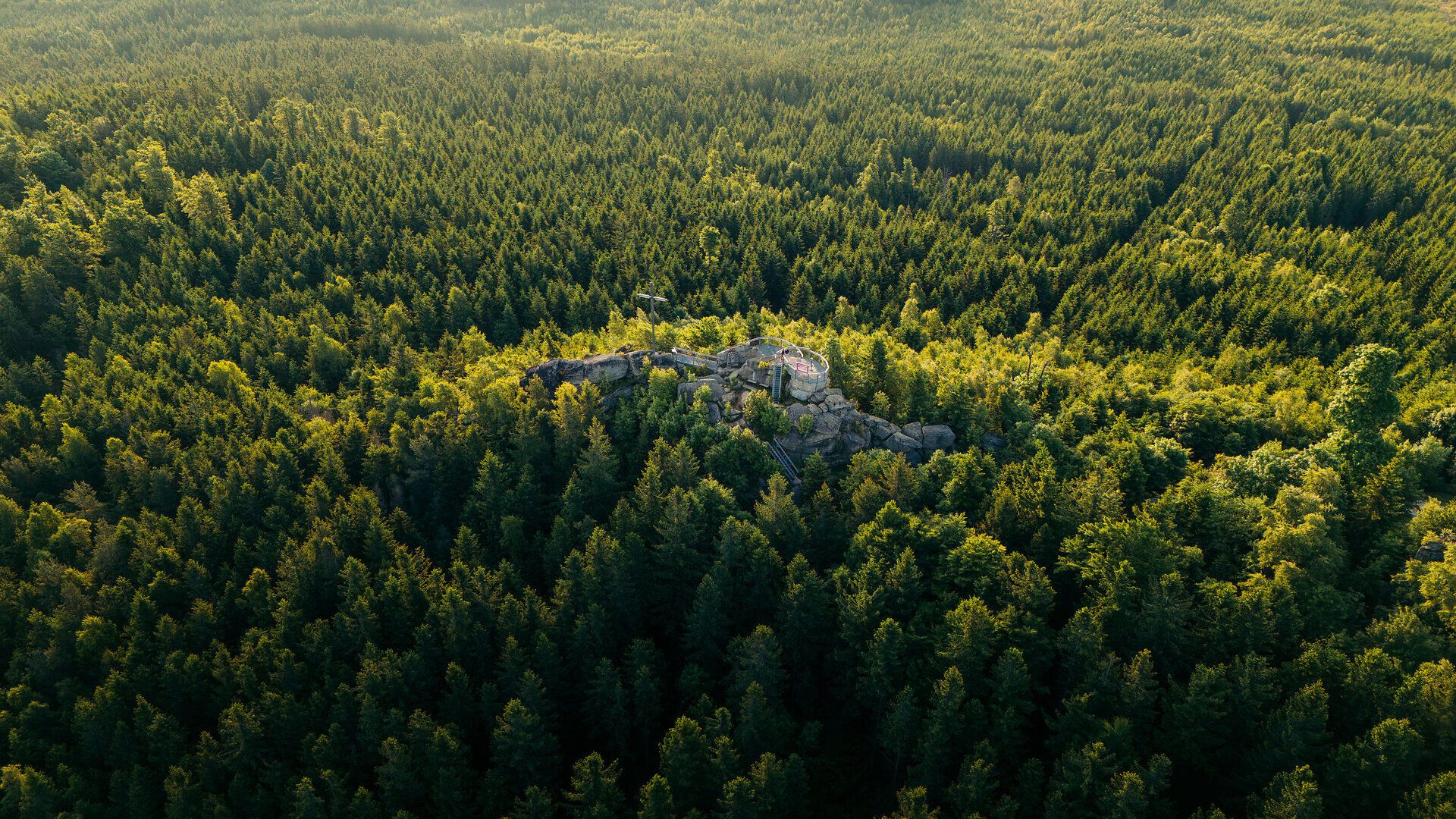 Aussichtsplattform auf einer Felsformation mit Blick über dicht bewaldete Hügel im Waldviertel aus der Vogelperspektive.
