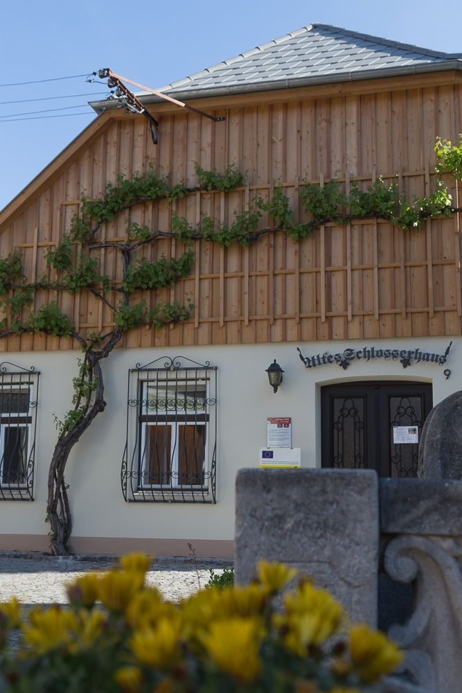 Fasáda starého zámečnického domu s dřevěným obložením a popínavými rostlinami.