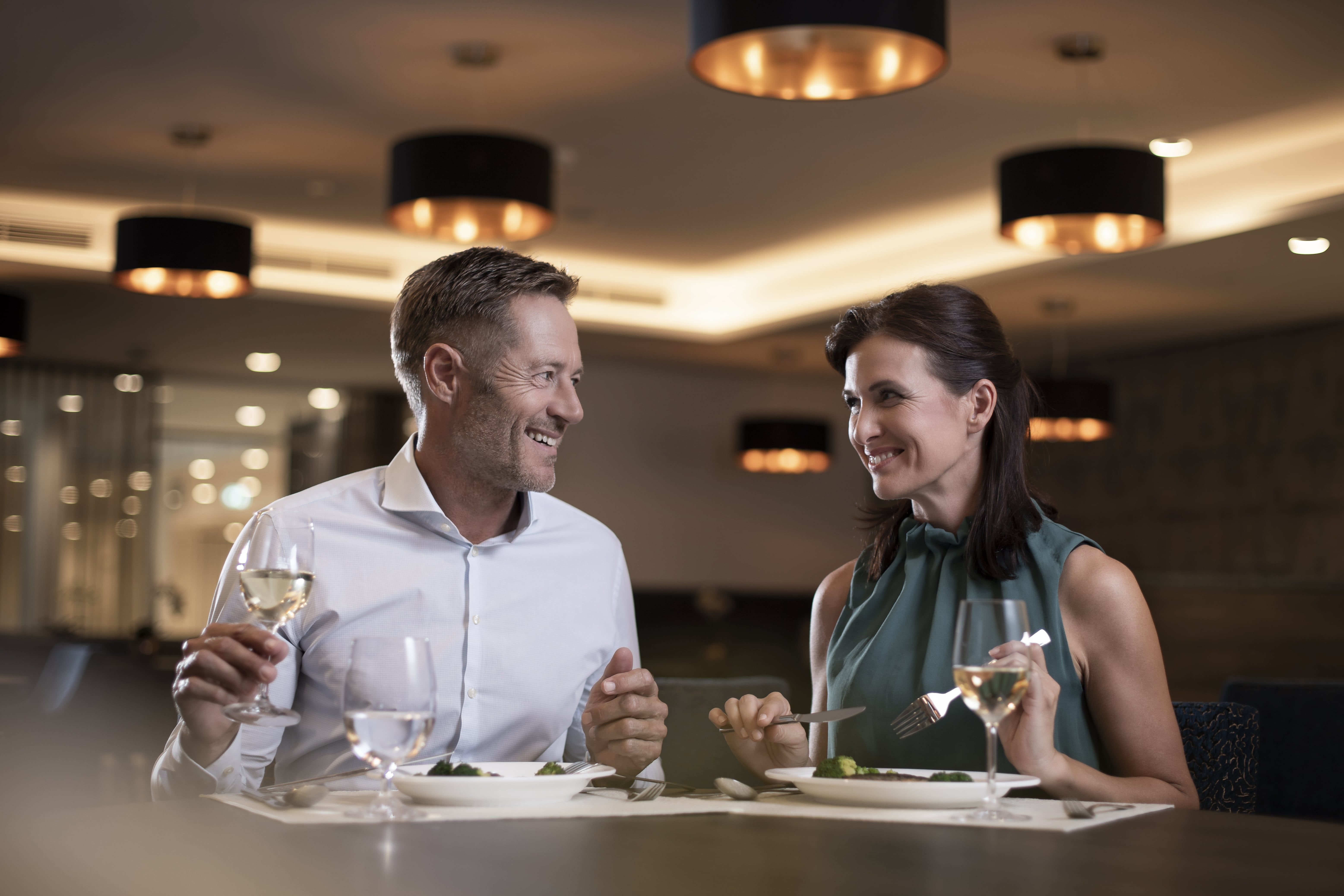 Pár sedí v elegantní restauraci a vychutnává si večeři s vínem.