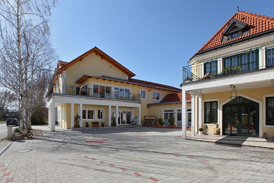 Vnější pohled na žlutou vinici s červenými střechami a dlážděným dvorem.