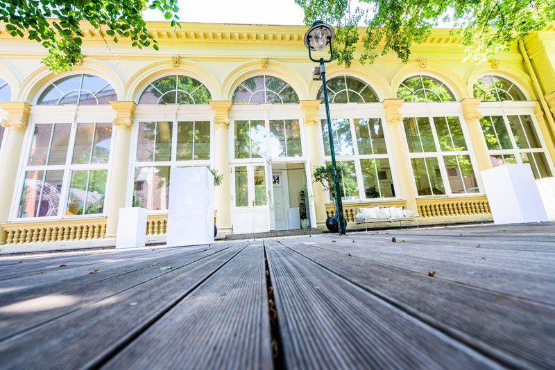 Vnější pohled na Kursalon Mödling s velkými okny a dřevěnou podlahou.