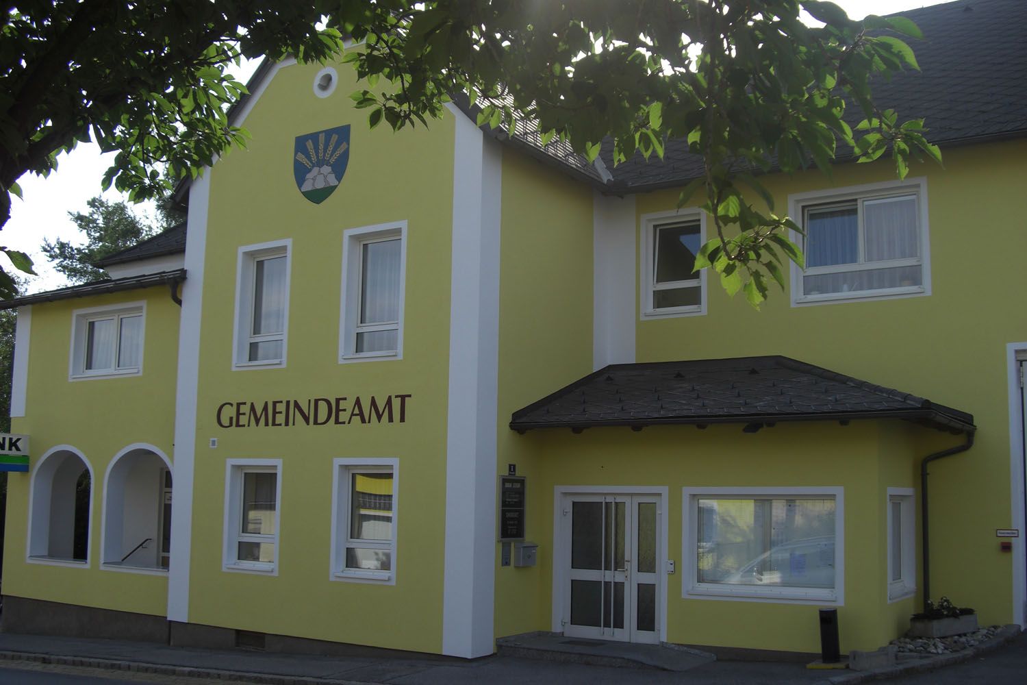 Žlutá budova s nápisem "GEMEINDEAMT" a erbem nad ní.