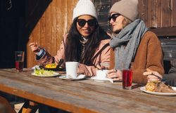 Dva běžkaři na zasněžené trase v zimní horské krajině.