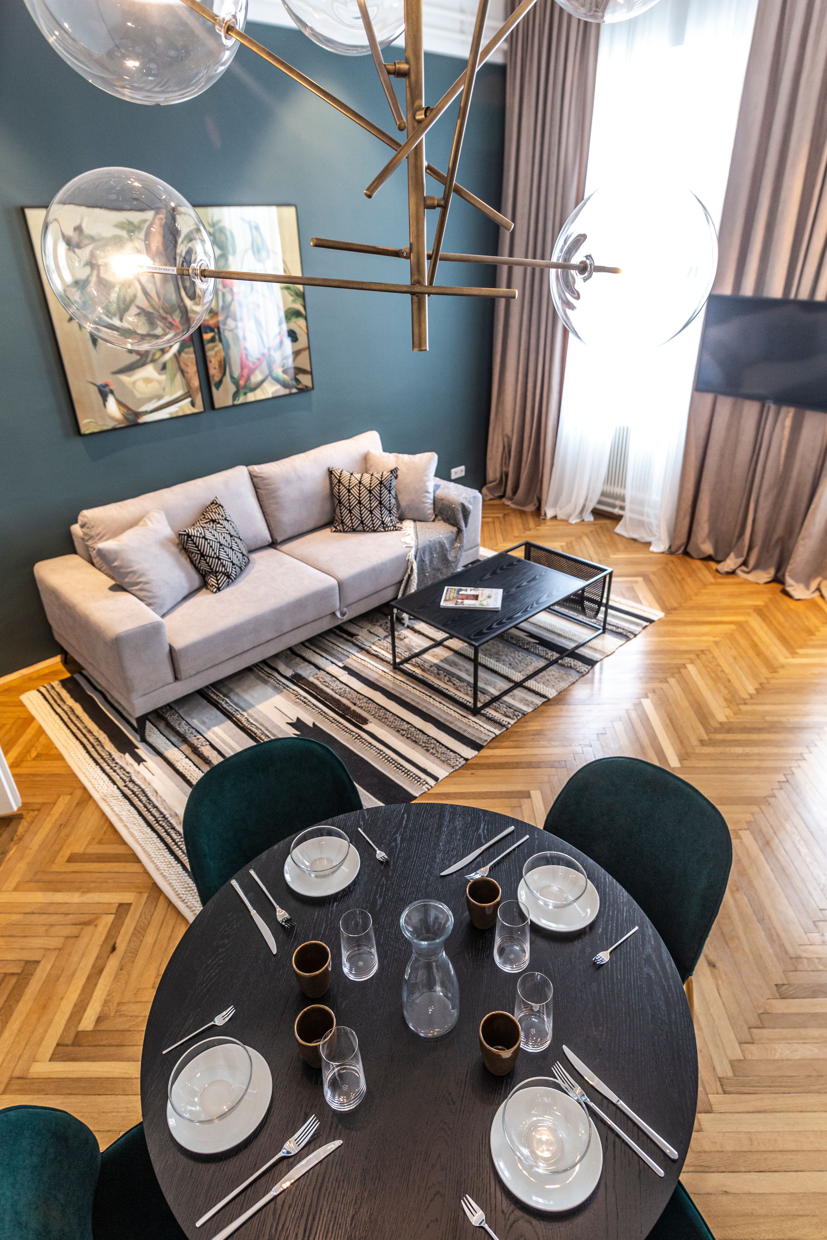 Moderní obývací pokoj s pohovkou, konferenčním stolkem, kobercem a jídelním stolem s prostíráním.