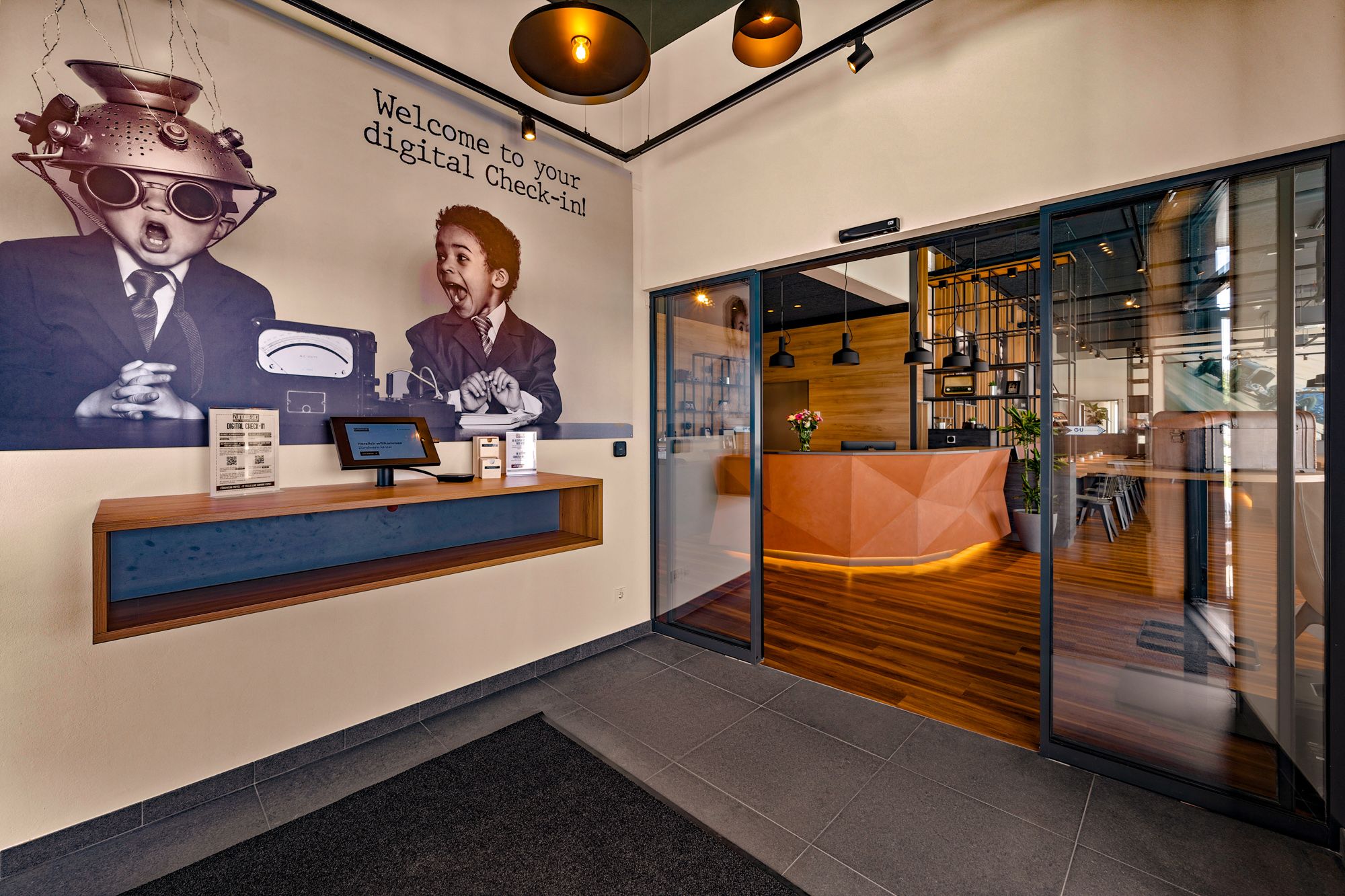Vstupní prostor moderního motelu s digitálním odbavením a stylovou recepcí.