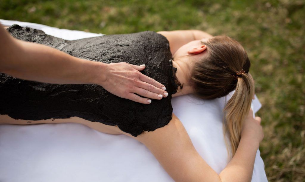 osoba dostane na záda bahenní zábal na volném prostranství.