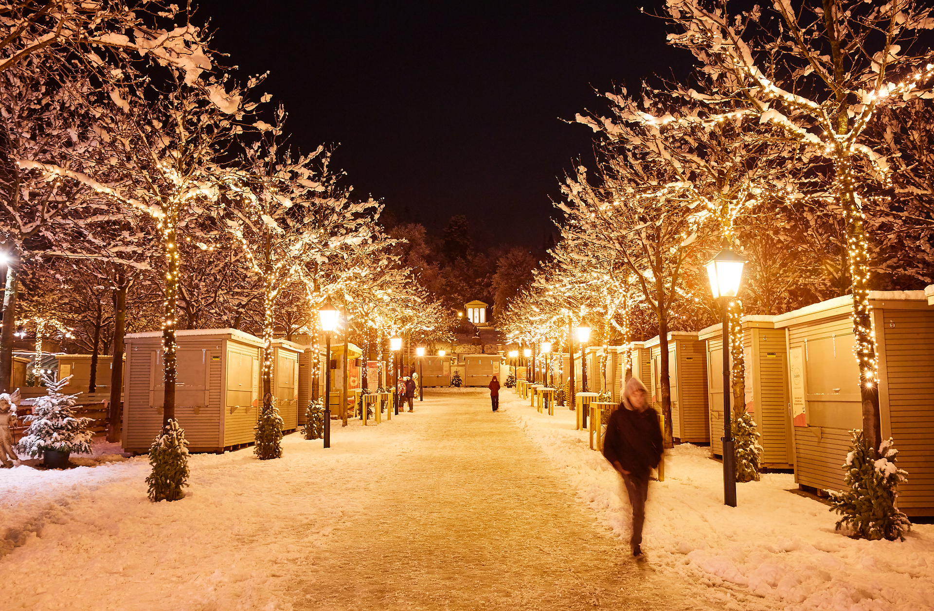 Der winterliche Kurpark erstrahlt in festlichem Glanz, während sanfte Schneeflocken die Wege bedecken. Lichter funkeln an den Bäumen und schaffen eine zauberhafte Atmosphäre, die zum Verweilen einlädt. Der Duft von Glühwein und frisch gebrannten Mandeln zieht durch die Luft und verspricht besinnliche Stunden auf dem Weihnachtsmarkt.