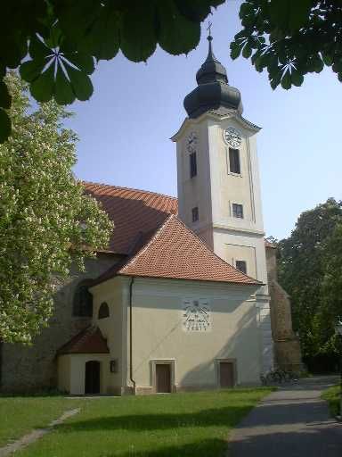 Farní kostel ve Zwentendorfu s věží a hodinami, obklopený stromy.