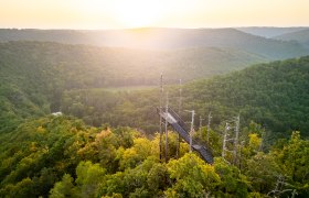 Vyhl&iacute;dkov&aacute; plo&scaron;ina v lese se z&aacute;padem slunce v pozad&iacute;.