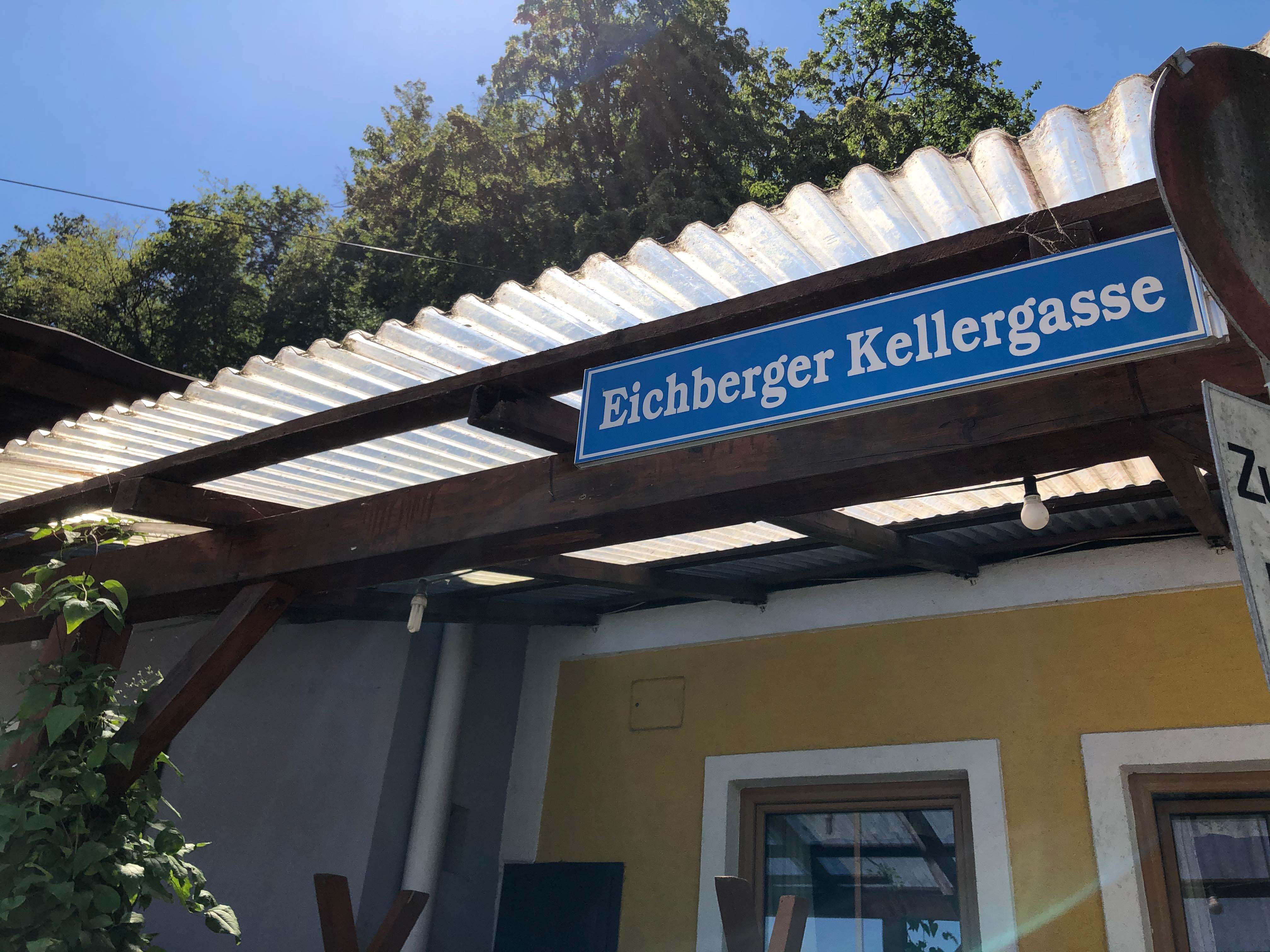 Nápis "Eichberger sklepní uličky" na budově se střechou z vlnitého plechu.