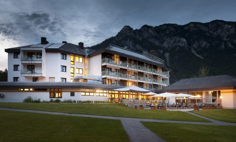 Osvětlená budova hotelu na pozadí hor za soumraku.