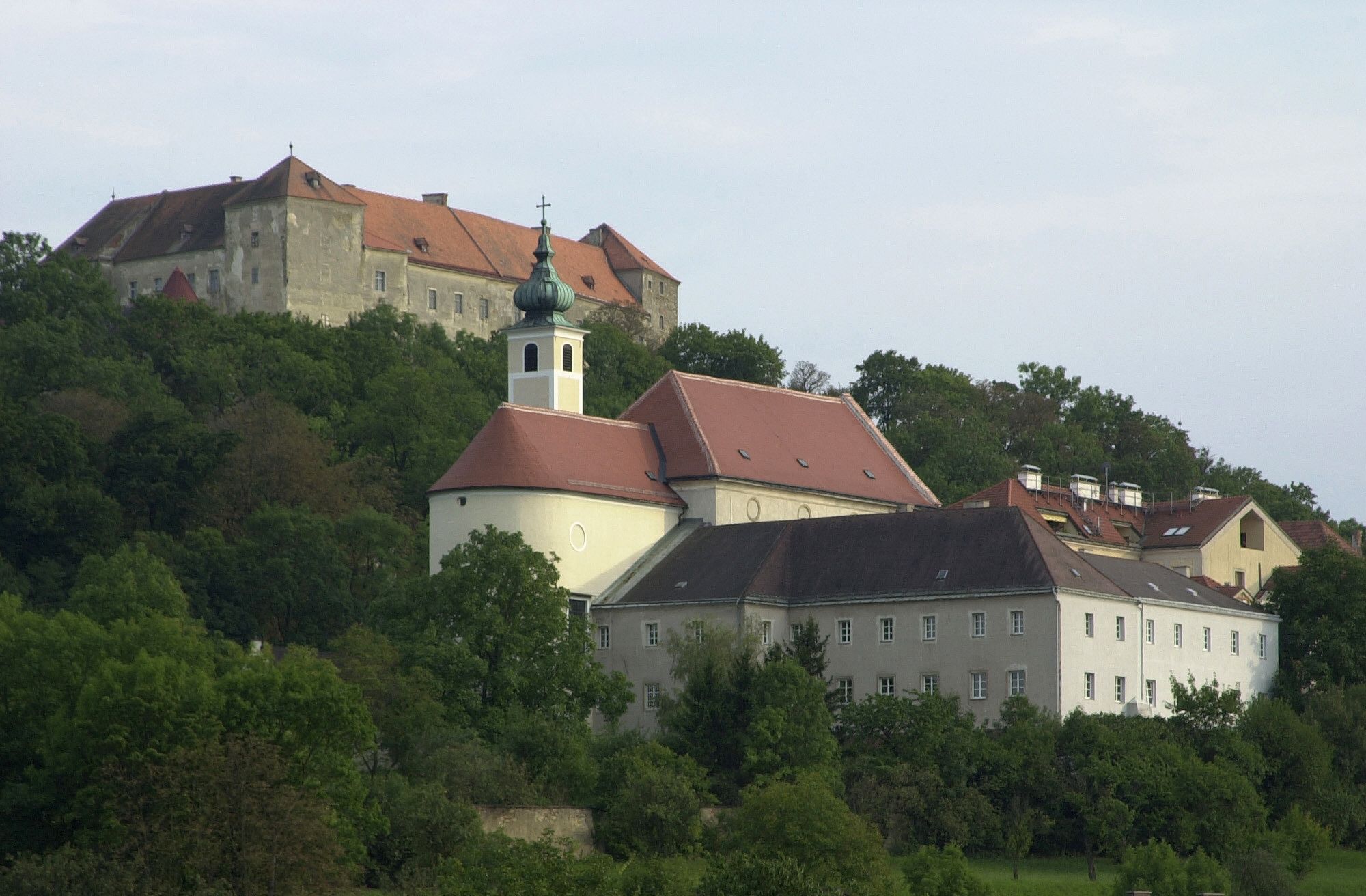 Hrad Neulengbach na kopci s okolními budovami a stromy.