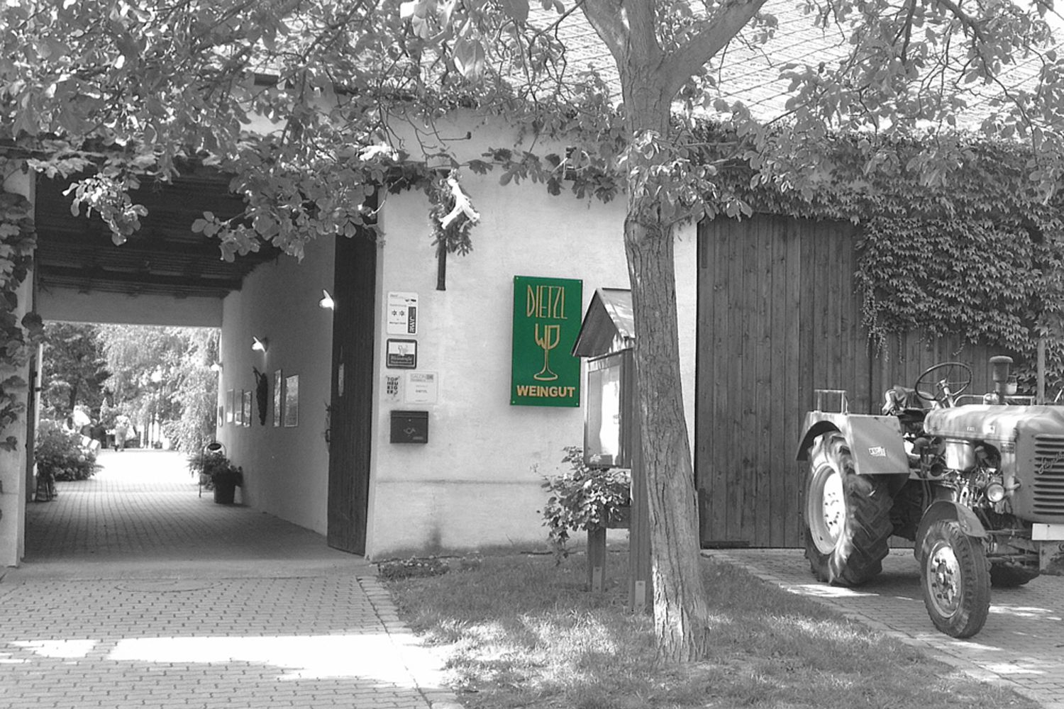Vchod do vinařství s nápisem "Dietzl Weingut" a traktorem vedle něj.