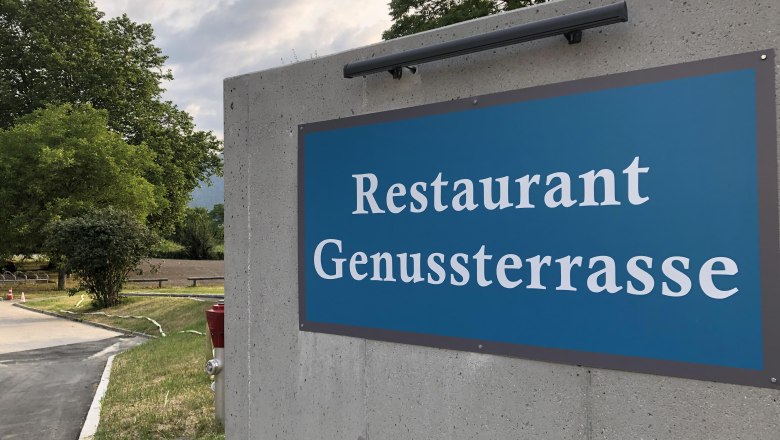 N&aacute;pis na restauraci "Genussterrasse" na betonov&eacute; zdi venku.