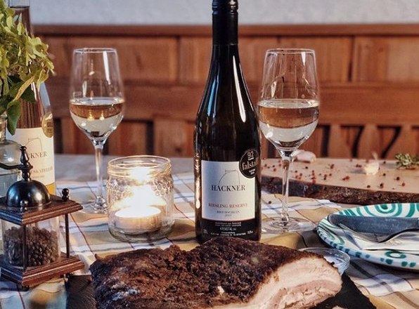 Stůl s lahv&iacute; v&iacute;na, dvěma skleničkami, sv&iacute;čkou a miskou na maso.