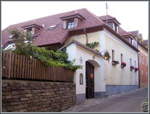 Tradiční dům s červenou taškovou střechou a květinovými truhlíky na oknech.