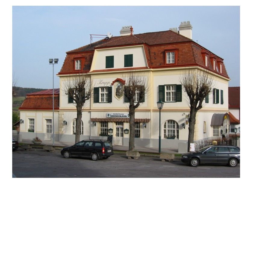 Dvoupatrová budova s červenými střešními taškami a zelenými okenicemi, označená jako Pension Bärenschlössl.