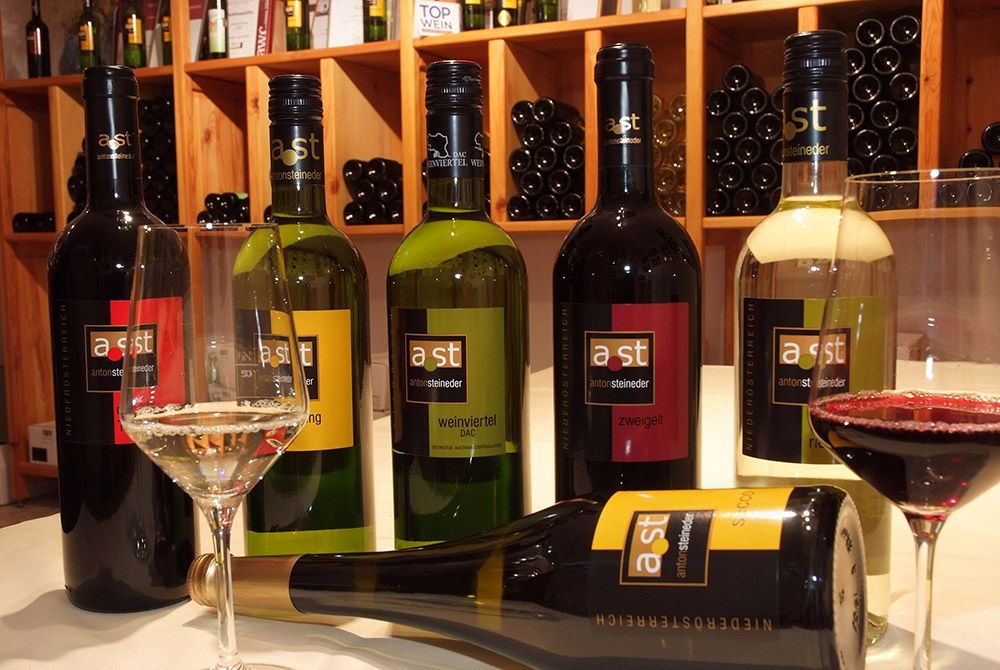 Různé láhve vína a sklenice na stole ve vinném sklípku.