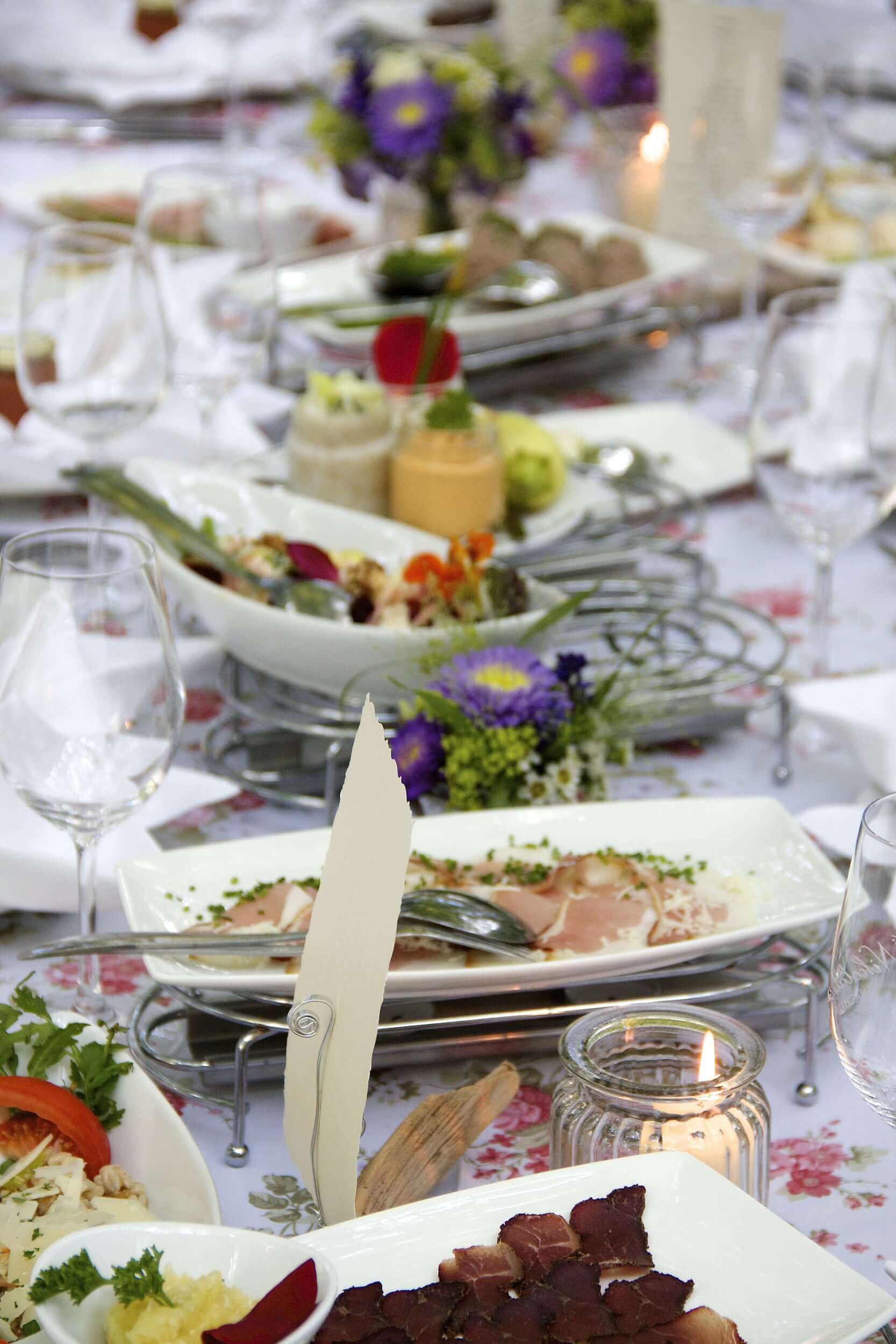 Prostřený stůl s různým nádobím a květinovou výzdobou.