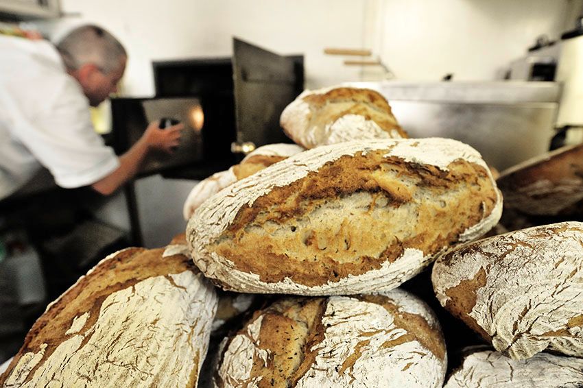 Čerstvě upečený chléb před pekařem obsluhujícím pec.