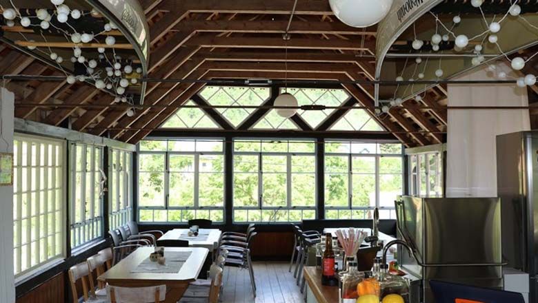 Pohled do interiéru světlé místnosti s dřevěnou střechou a velkými okny.