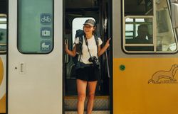 Frau steigt gerade aus dem goldenen Triebwagen der Waldviertelbahn lächelnd aus