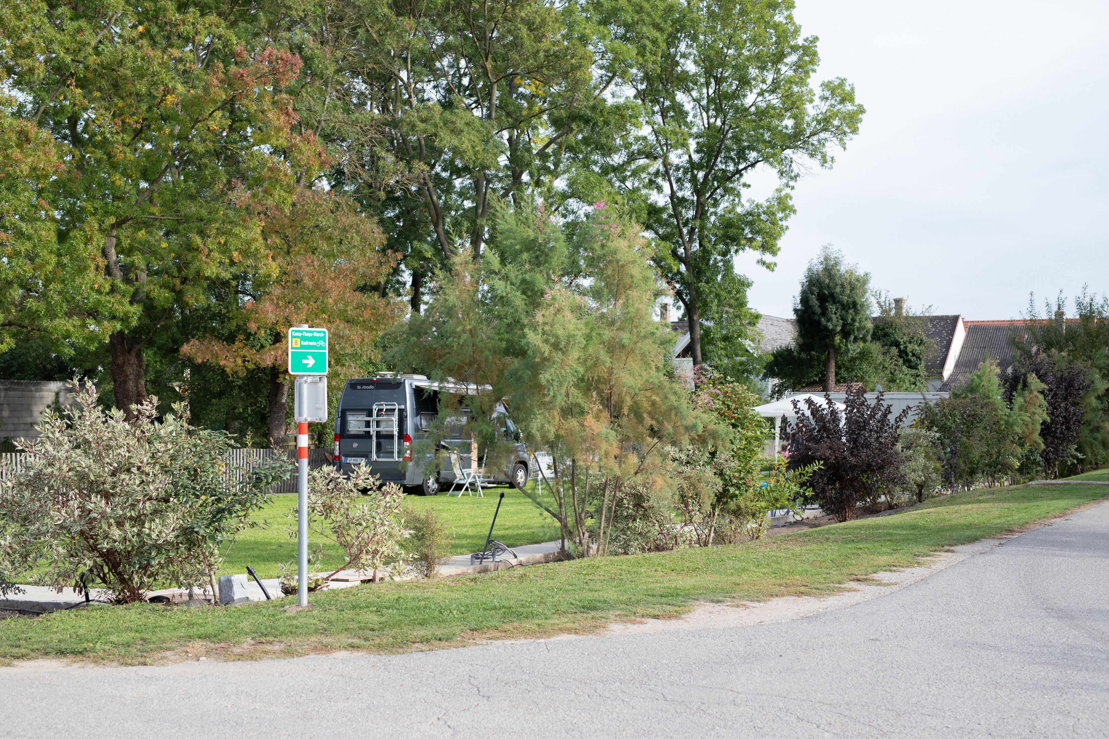 Kemp s obytným vozem a stromy v pozadí.