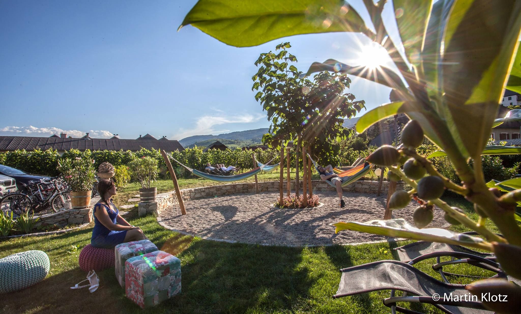 Středomořská zahrada s houpacími sítěmi a odpočívajícími lidmi.