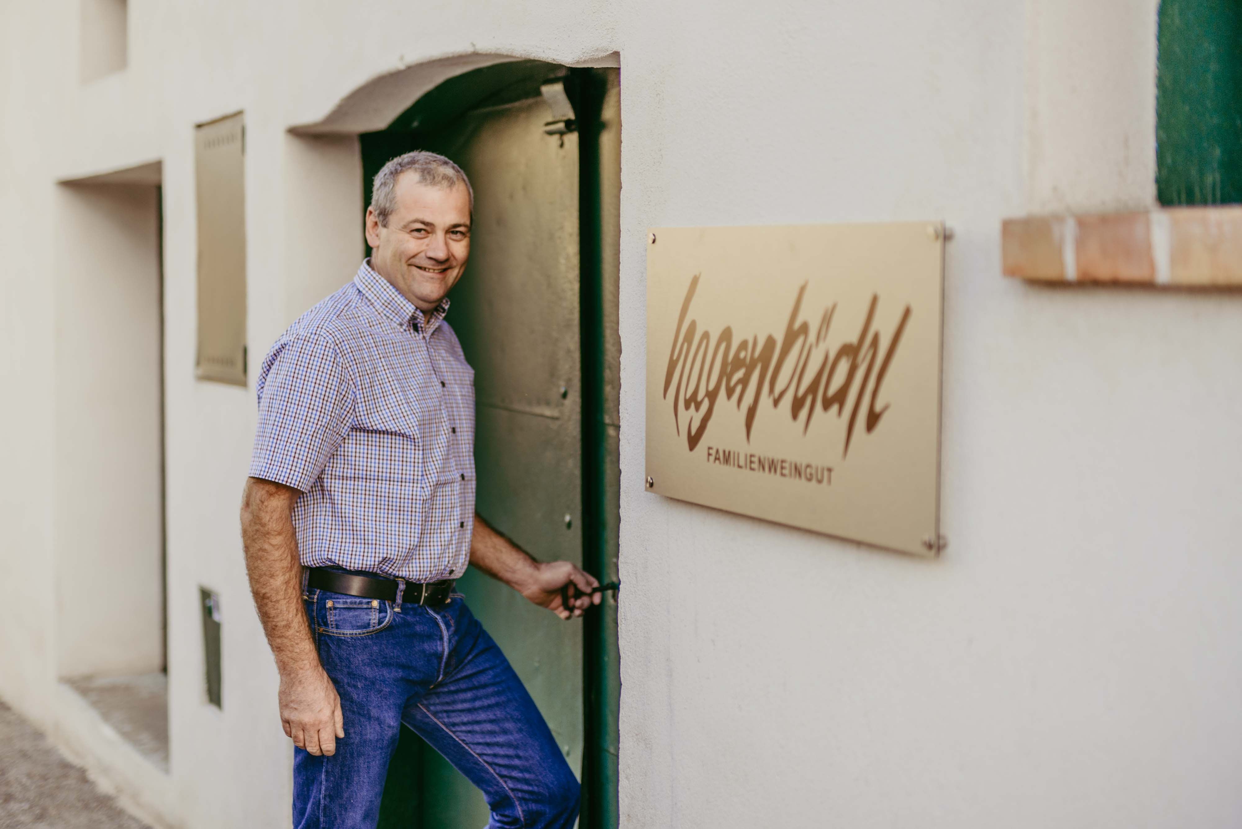 Muž otevírá dveře vedle nápisu "Hagenbüchl Familienweingut".