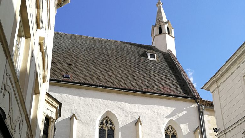 Bürgerspitalskirche v Kremži se špičatou věží a gotickými okny.